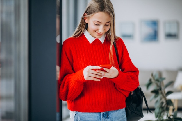 Girl student in red sweater using phone