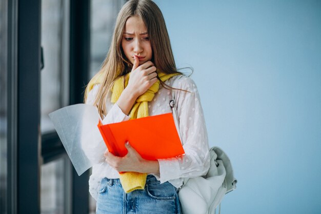 Girl student standing with colorful folders