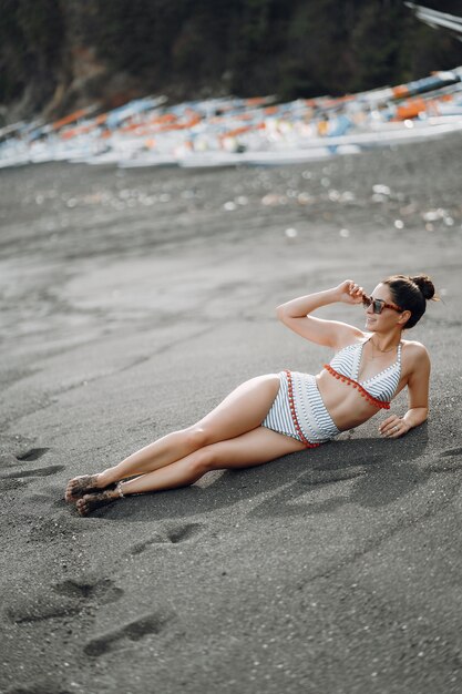スタイリッシュな水着の女の子がビーチで休憩