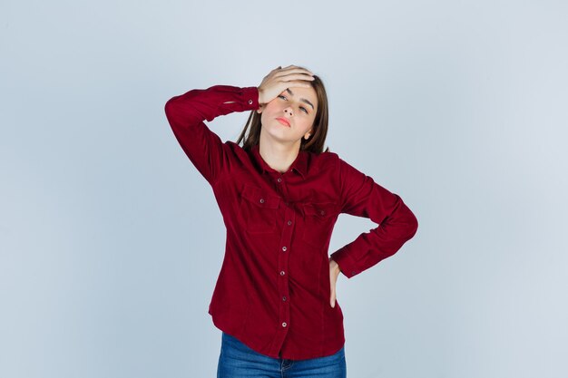 Girl suffering from headache in casual shirt and looking distressed.