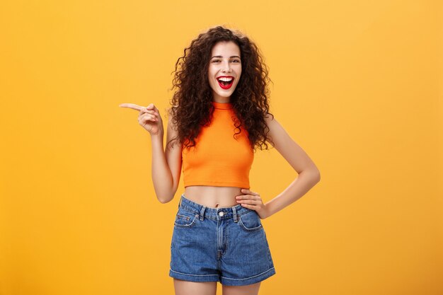 Girl suggesting check out cool copy space attractive young happy and energizing curlyhaired female i...