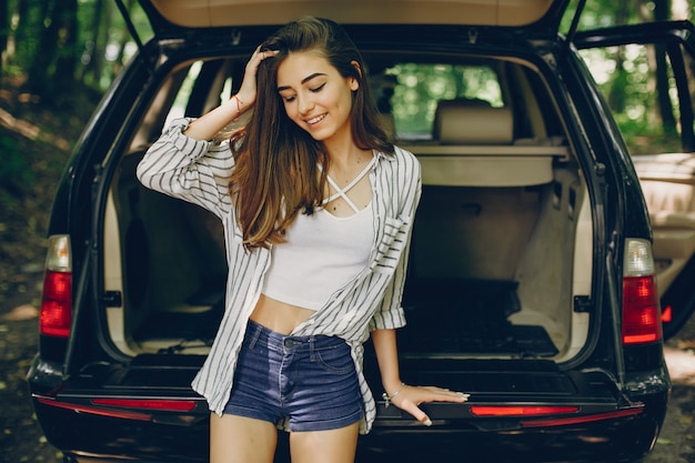 Girl in a summer park near car