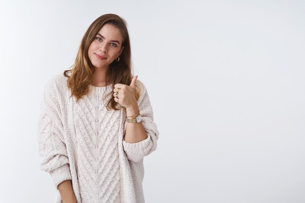 Girl supporting you giving thumbs up cheering expressing viewpoint liking product, approving service recommending, tilting head smiling satisfied happily, looking tender wearing cozy loose sweater