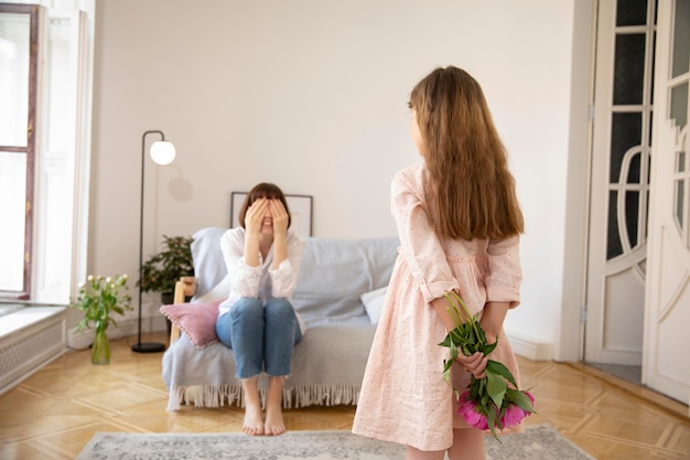 Girl surprising mother with flowers medium shot