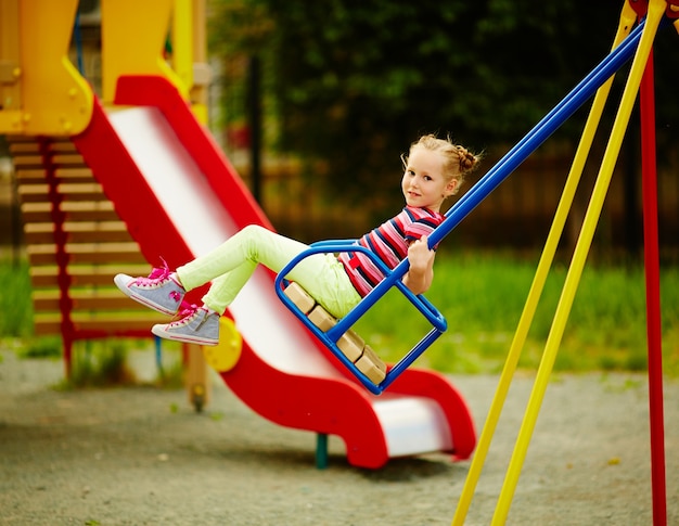 Girl on a swing in the playground at summertime