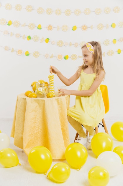 Girl at table surrounded by balloons and lemons