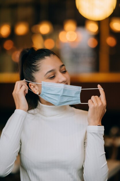 Девушка снимает защитную медицинскую маску для лица