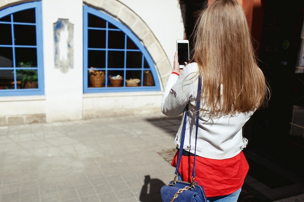 Free photo girl takes a picture of a blue window on her phone