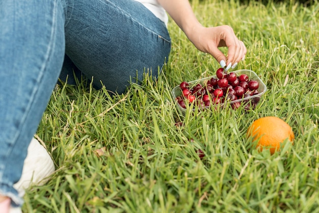 Girl taking cherries sitting on the grass