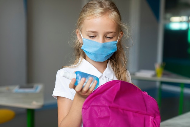 Free photo girl taking the disinfectant out  of her backpack