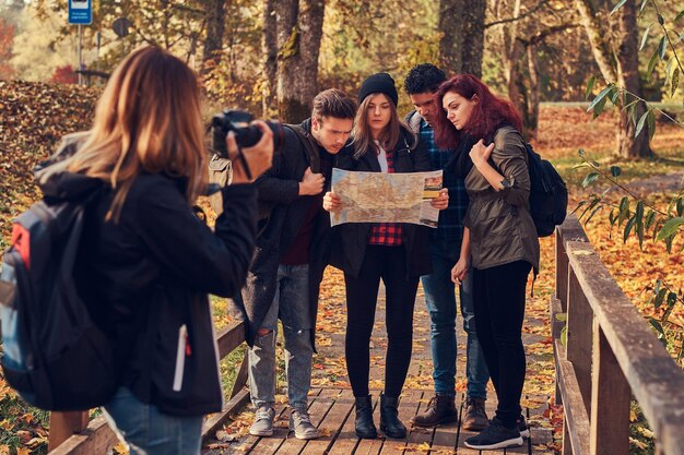 友達の写真を撮る女の子。森の中をハイキングする若い友人のグループ。旅行、ハイキング、冒険のコンセプト。