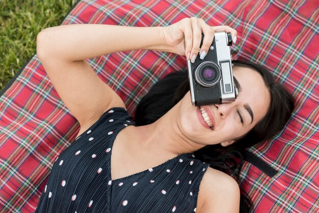 Foto gratuita ragazza che cattura una foto sulla coperta da picnic