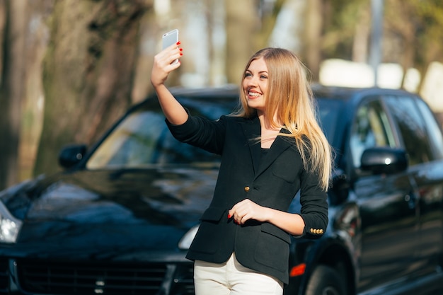 Girl taking selfie near new car