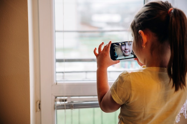 Ragazza che cattura selfie vicino alla finestra