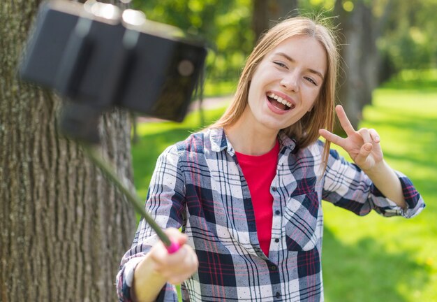 屋外で彼女の携帯電話でselfieを取っている女の子