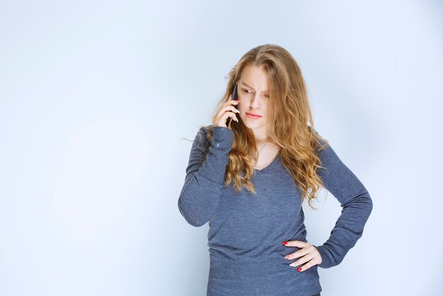 Girl talking to the phone and looks terrified.