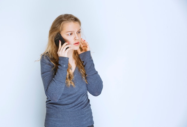 Girl talking to the phone and looks terrified.