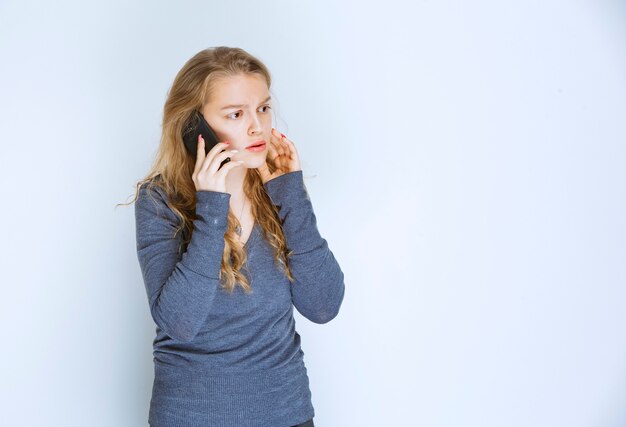 Girl talking to the phone and looks terrified.