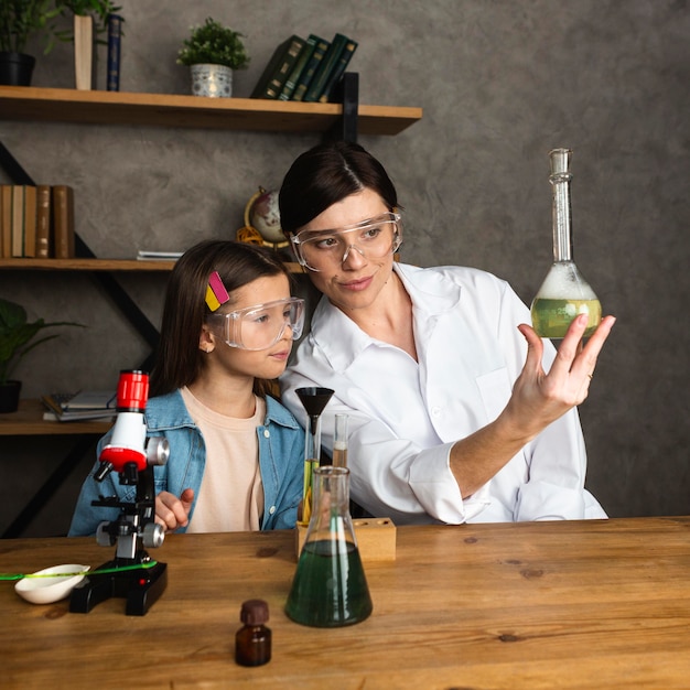 試験管と顕微鏡で科学実験をしている少女と教師