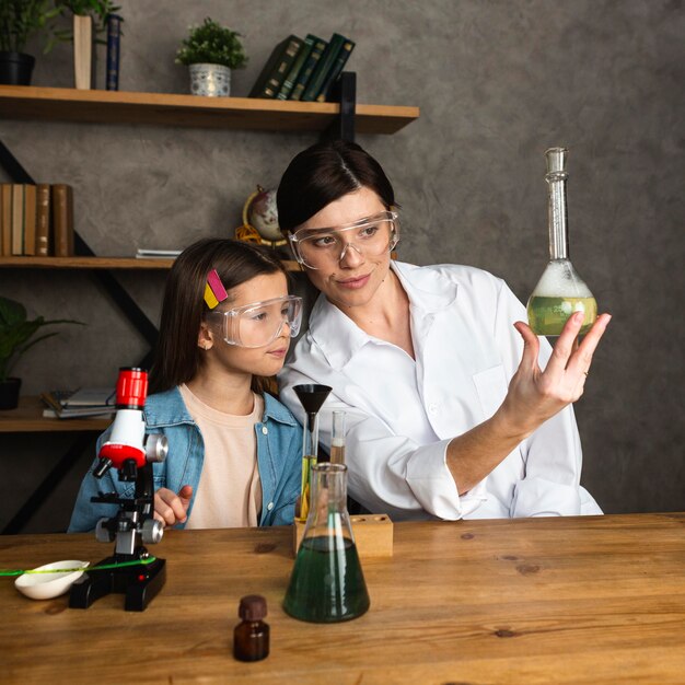 Girl and teacher doing science experiments with test tubes and microscope