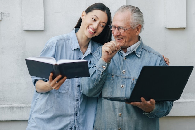 Girl teaching her grandfather how to use a laptop