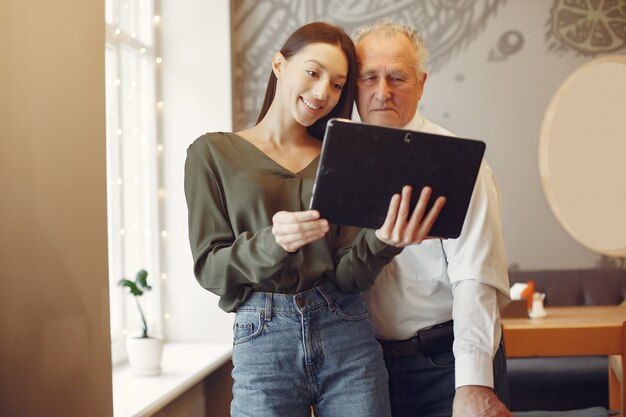 Girl teaching her grandfather how to use a tablet