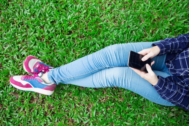 Girl Texting on Smartphone and Sitting on Grass