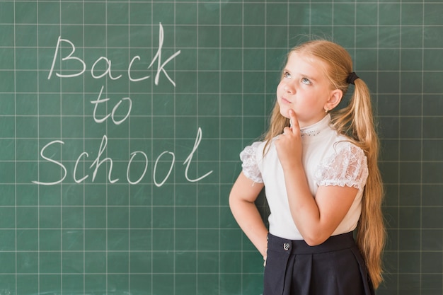 Free photo girl thinking standing near blackboard