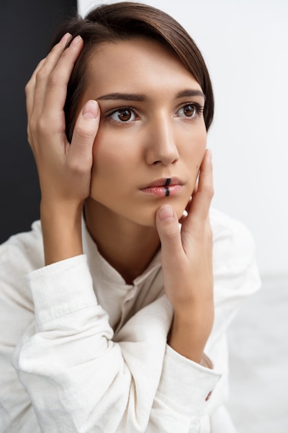 Girl touching face with hands over black and white wall