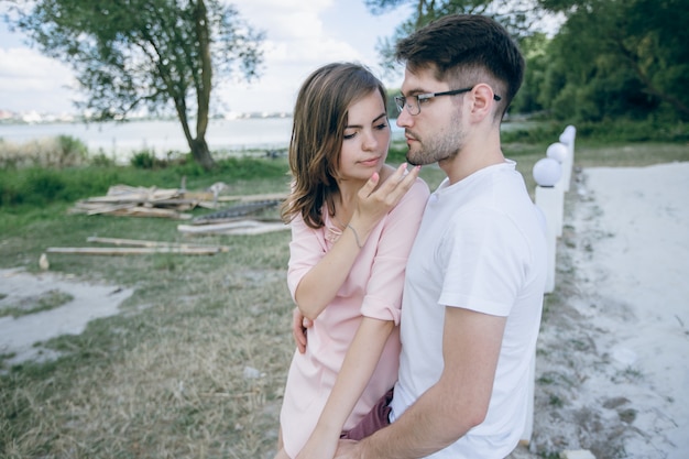 Girl touching her boyfriend's chin on a white fence