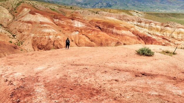 Girl traveler with a backpack stands on the edge of the red canyon. red mountains on mars
