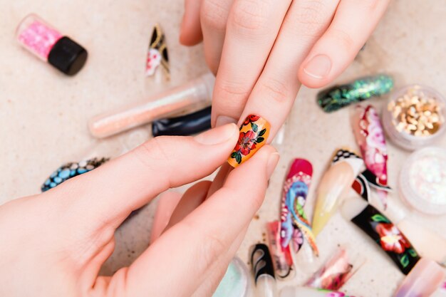 Girl trying artificial nails tips with flower nail design