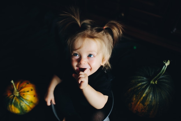 Free photo girl tucked in a bowl with pumpkins around and mouth open