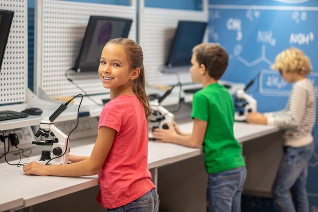 Girl turned to camera standing near microscope