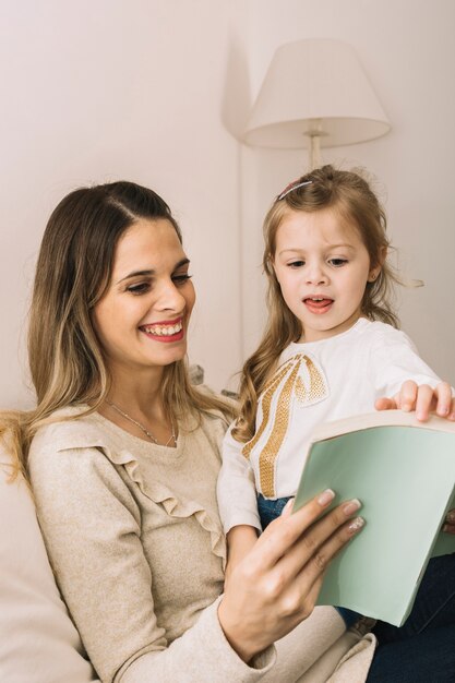 Girl turning pages of book while reading with mother