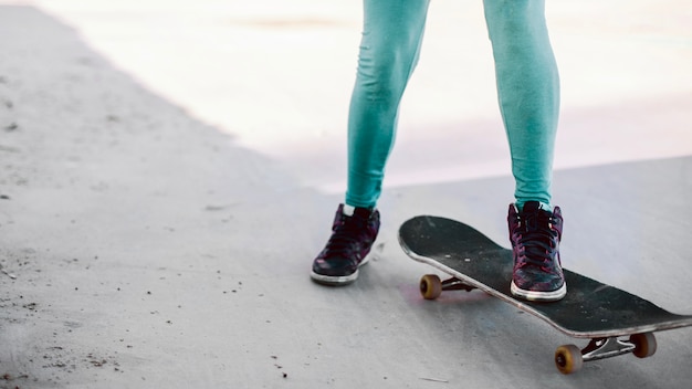 Девушка в бирюзовых лосинах, стоящих на скейтборде