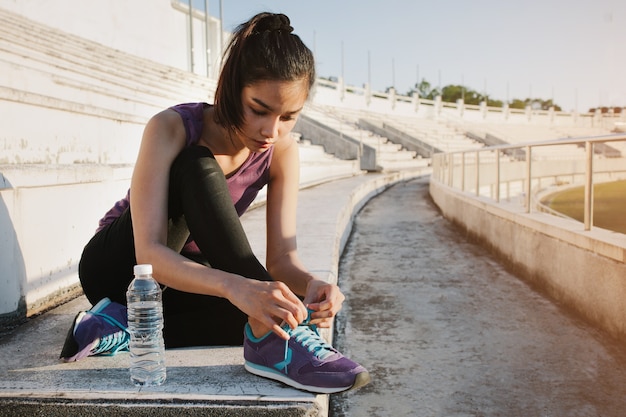 Girl tying her sneakers next to a water bottle