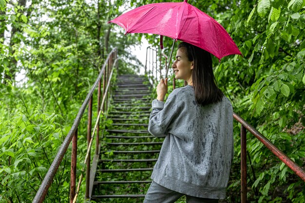 雨の中、春の森を散歩する傘の下の女の子。