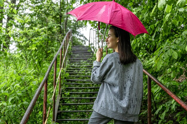 빗 속에서 봄 숲에서 산책에 우산 아래 소녀.