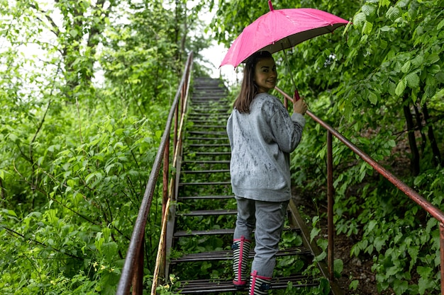 雨の中の春の森を散歩する傘の下の女の子