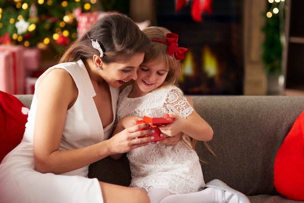 Free photo girl unwrapping christmas gift box with mummy