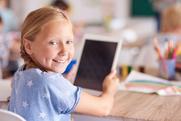 Девушка с помощью цифрового планшета в школе