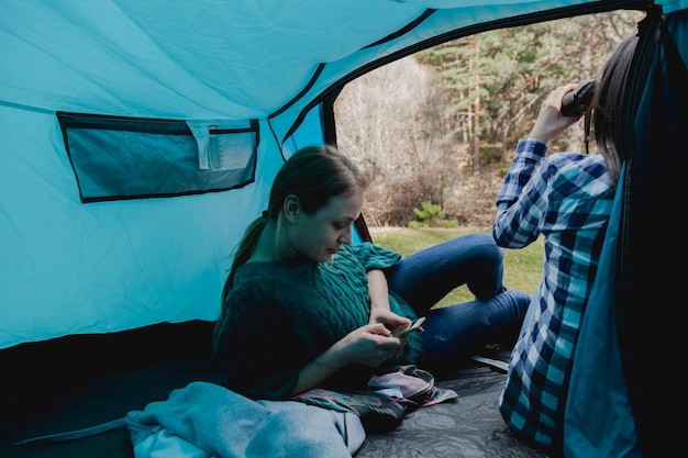 Девушка, используя свой мобильный телефон в палатке