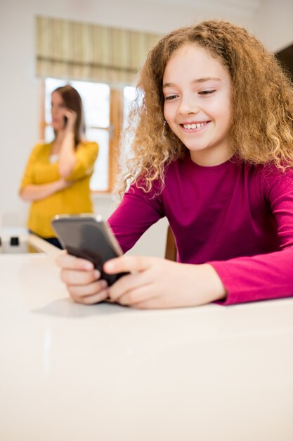 Girl using mobile phone in kitchen