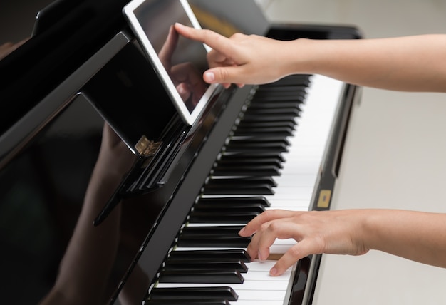 Foto gratuita ragazza utilizzando un tablet per imparare a suonare il pianoforte