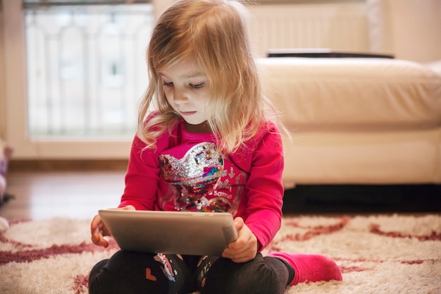 Girl using tablet on living room floor