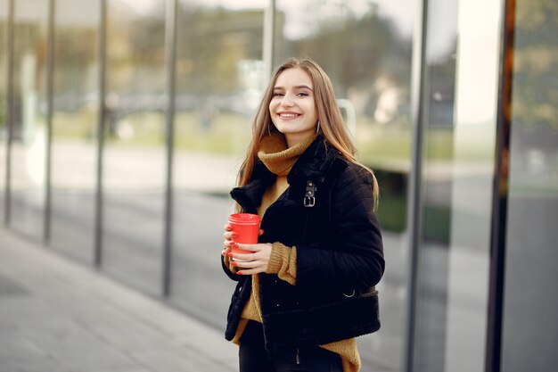 春の街を歩いて、彼女の手でコーヒーを保持している女の子