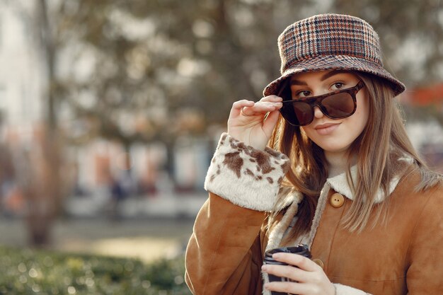 Girl walking in a spring sity and hold coffee in her hand