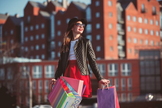 The girl walking with shopping bags on city streets at sunny day