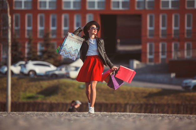 Foto gratuita ragazza che cammina con lo shopping per le strade della città